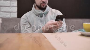 一个面目全非的男人<strong>坐在餐馆</strong>里，在离焦时使用智能手机。 慢动作